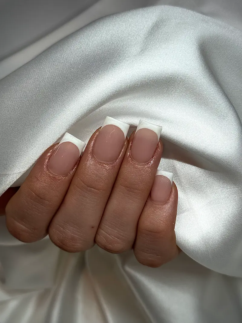 Classic white French tip manicure on natural nails at our professional nail salon in Fribourg